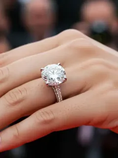 Close-up of a celebrity engagement ring, large diamond, sparkling, on a hand at a red carpet event.